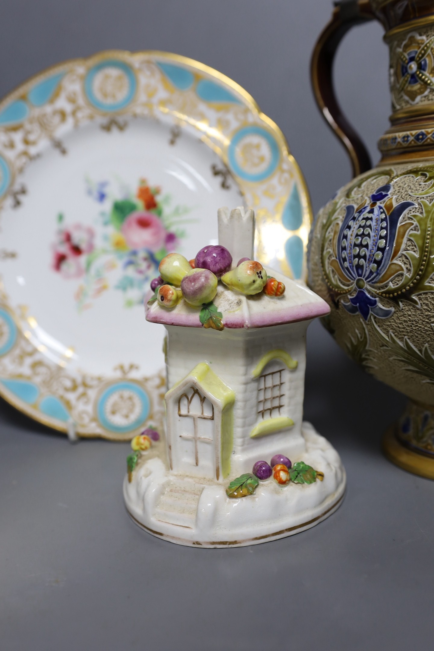 A Mettlach stoneware stein, 29.5 cm high, a German blue stoneware stein, a Staffordshire porcelain cottage pastille burner and an English porcelain floral plate